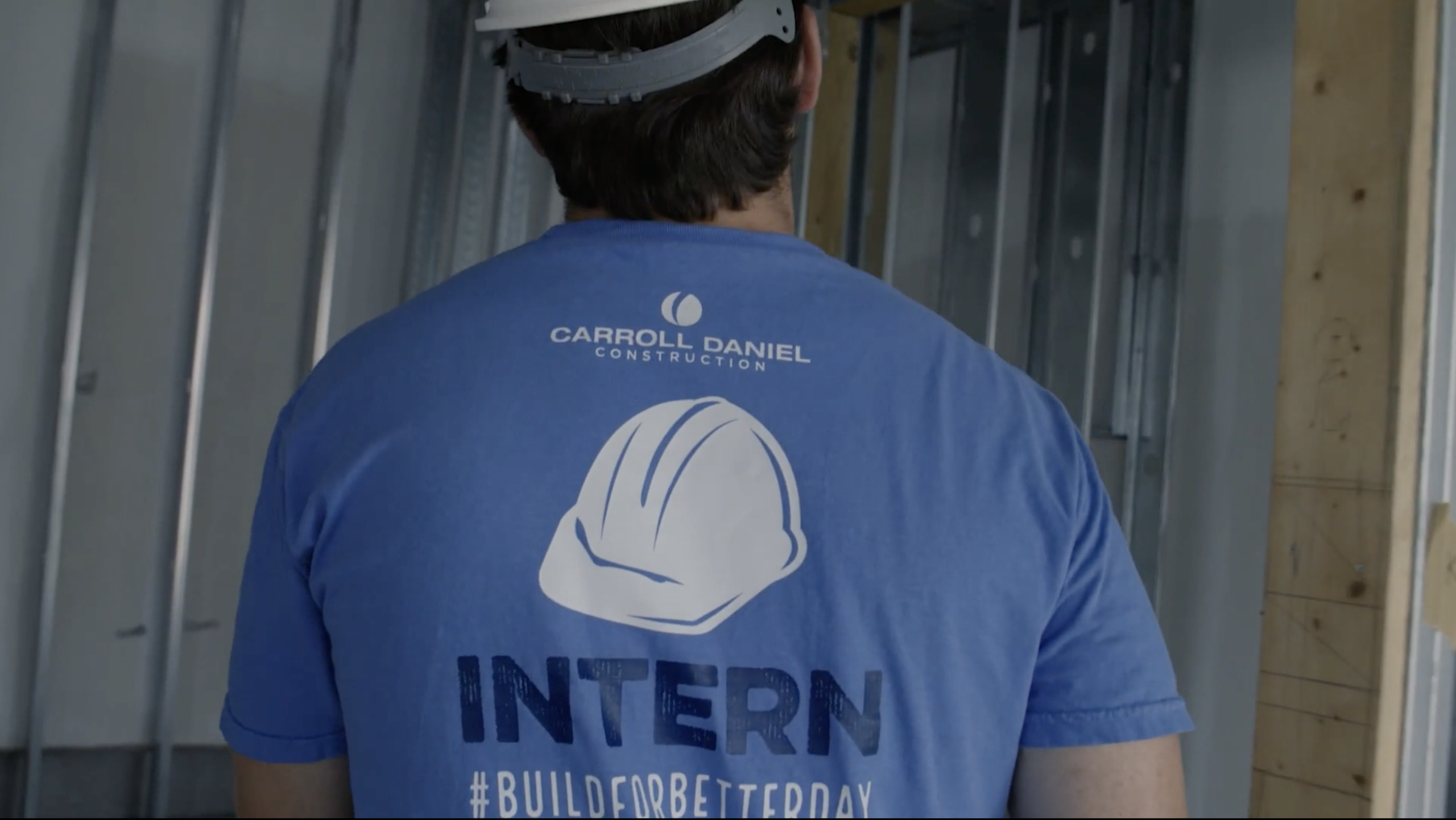 back of an intern wearing a carroll daniel construction t shirt and a hard hat